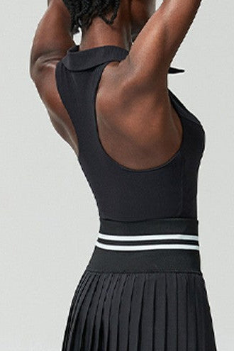 Person wearing a black pleated tennis skirt with white stripes on a white background